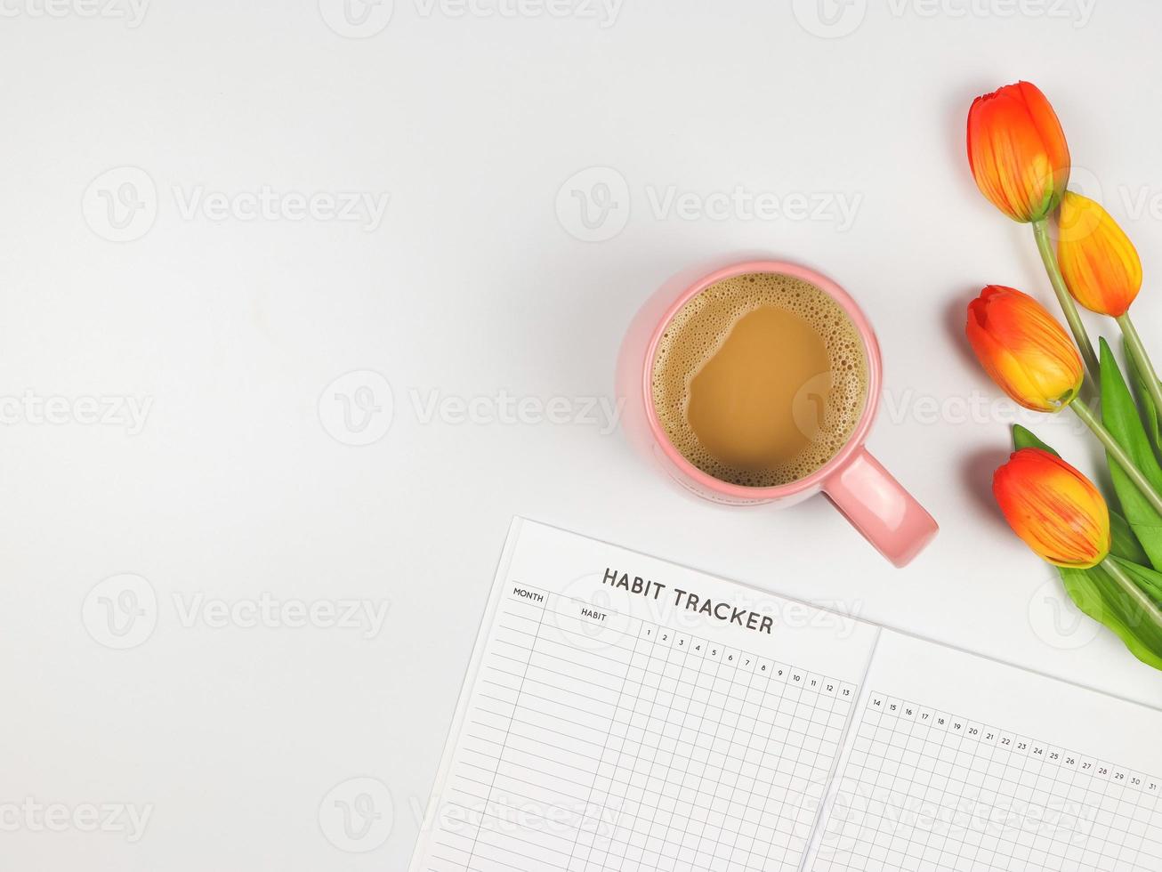 flat layout of Habit tracker book, cup of coffee and tulips on white background. photo