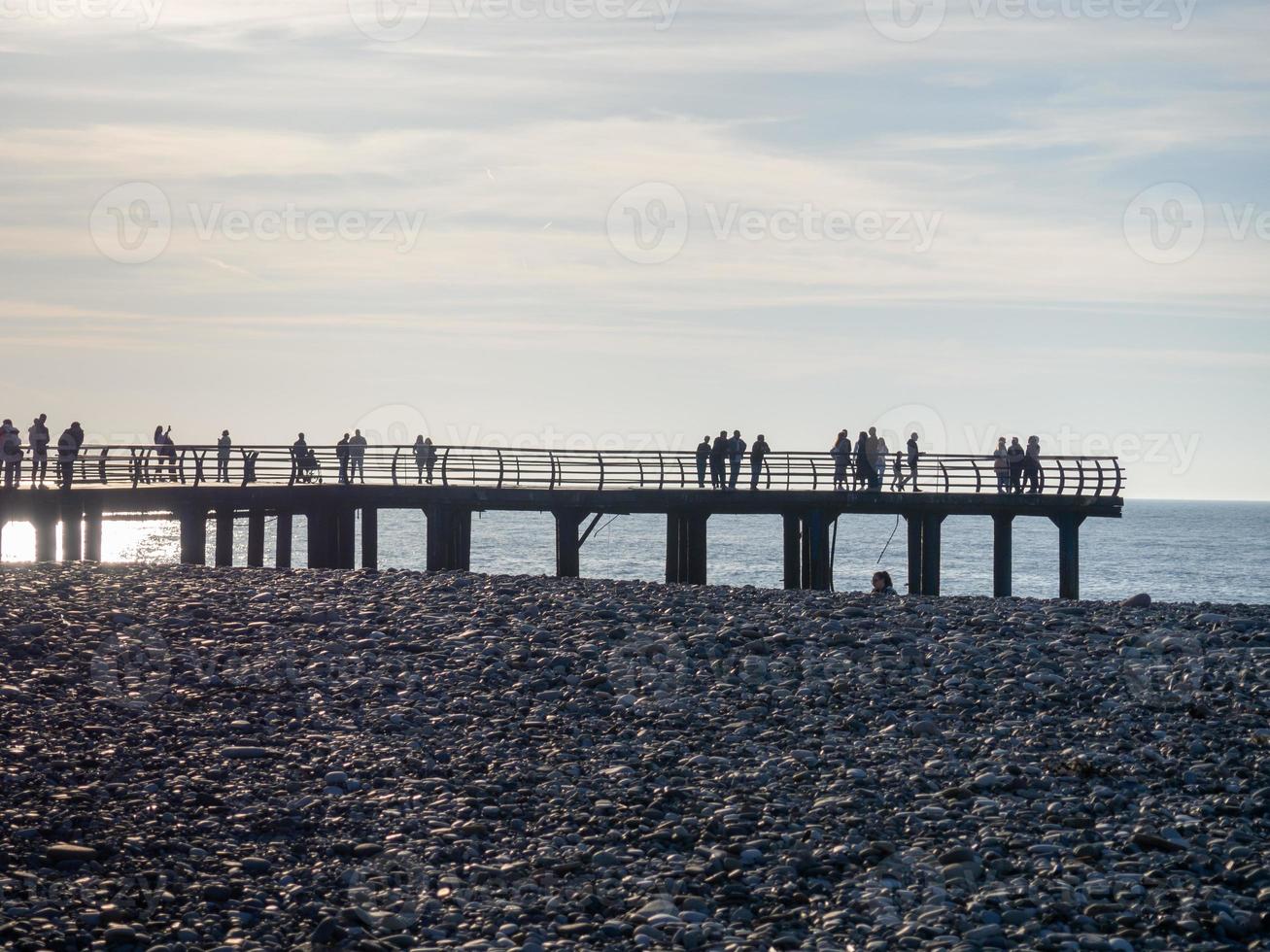 Silhouettes of people on the bridge on the seashore. People see off the sunset. Sea coast. Pier on the sea. photo
