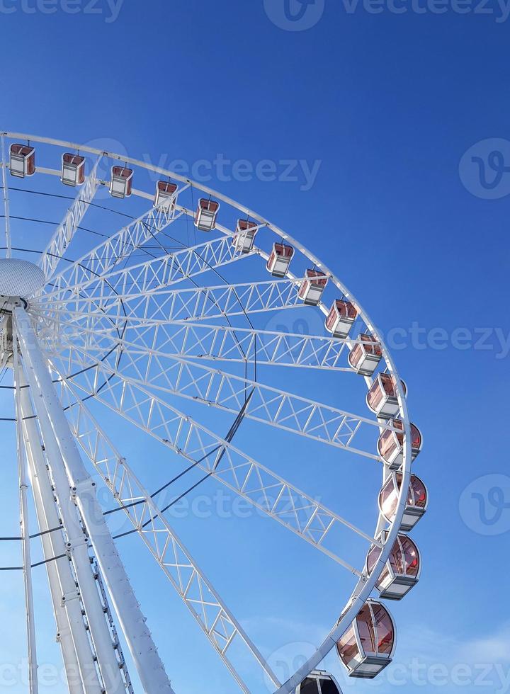 Right part of white giant ferris wheel against a bright blue sky in the midday light. Krakow, Poland, Europe. Vertical photo. photo