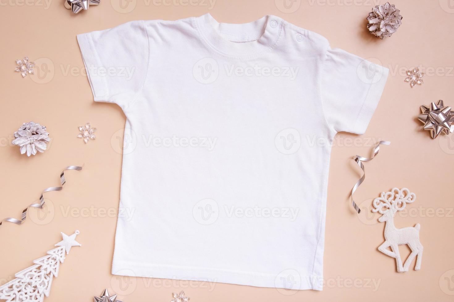 Baby t-shirt mockup for logo, text or design on beige background with winter decotations top view. photo