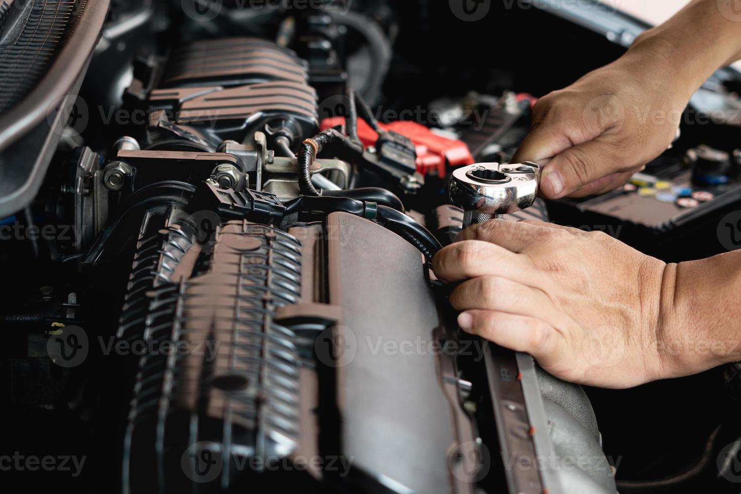 llave de primer plano en la mano mecánico masculino repara el coche en el garaje. mantenimiento de automóviles y concepto de garaje de servicio automático foto