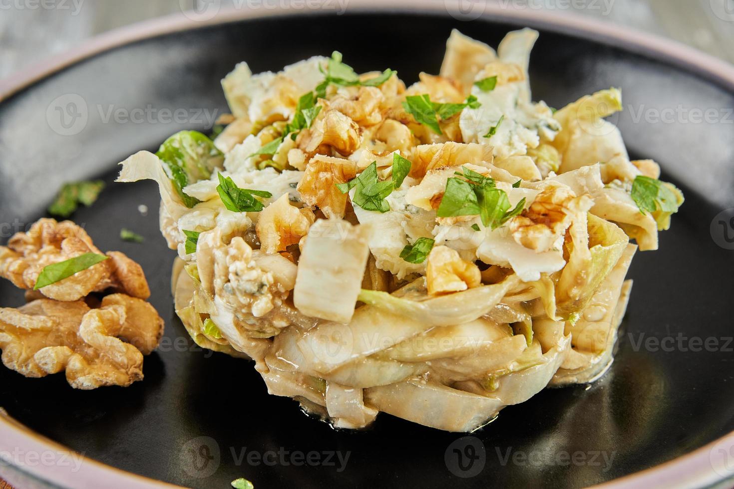 Endive chicory salad with Roquefort sauce on a black plate photo