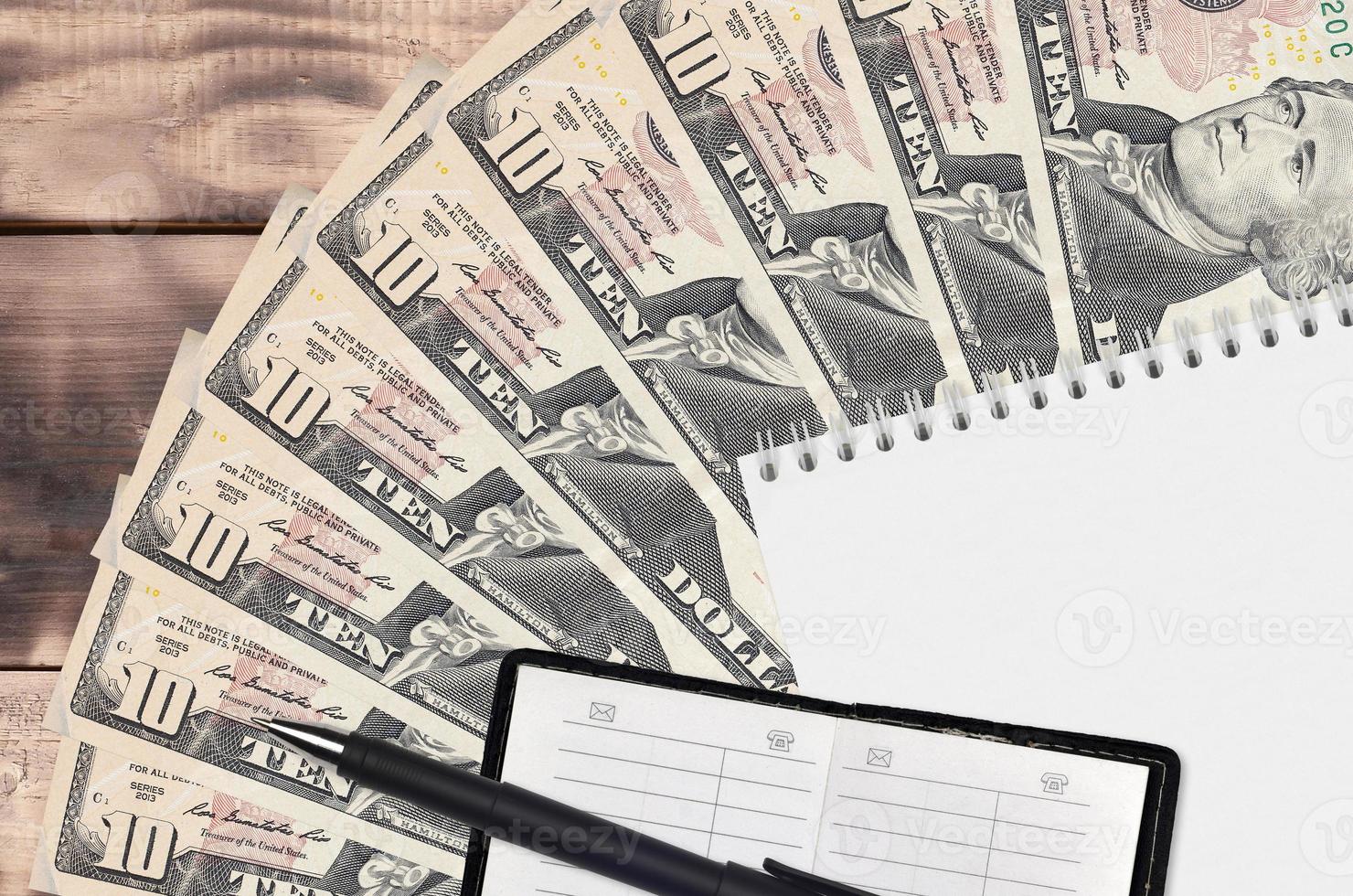 10 US dollars bills fan and notepad with contact book and black pen. Concept of financial planning and business strategy photo