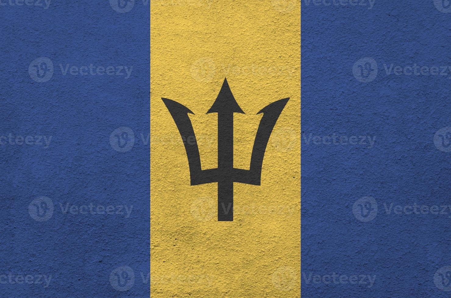 Barbados flag depicted in bright paint colors on old relief plastering wall. Textured banner on rough background photo