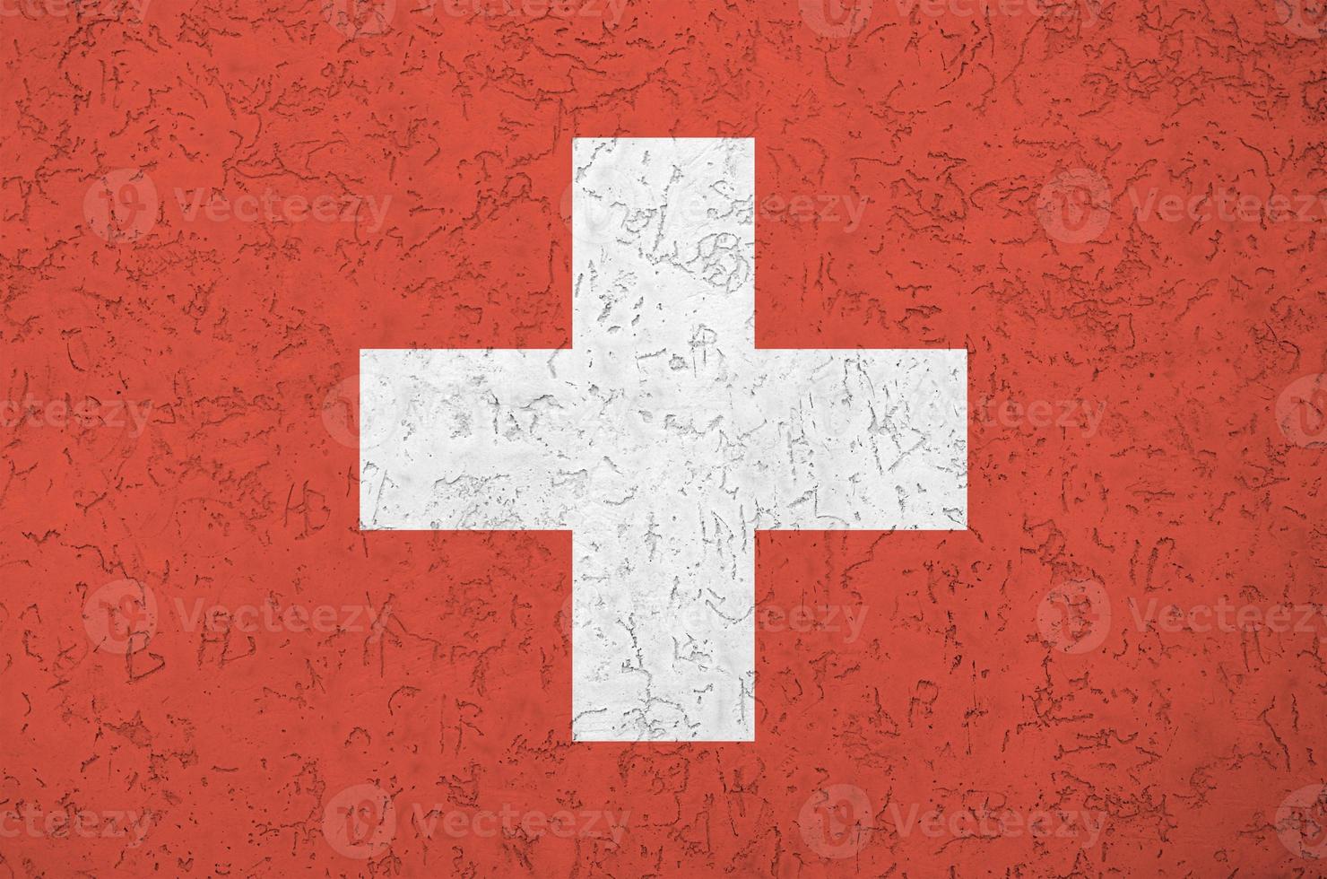 Switzerland flag depicted in bright paint colors on old relief plastering wall. Textured banner on rough background photo