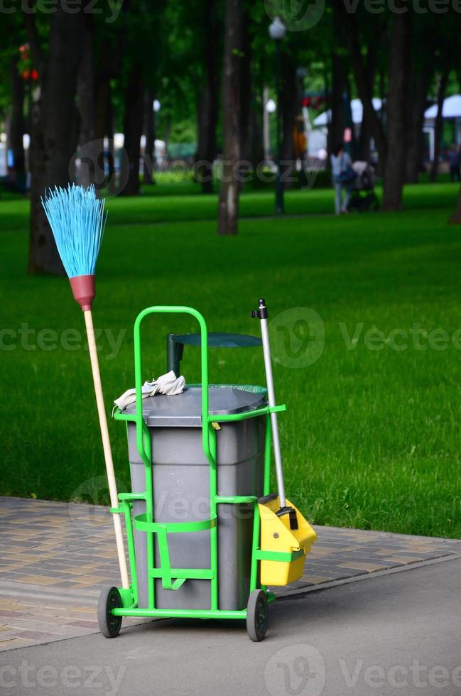 Cleaning service cart full of supplies and equipment along with grey trash bin photo