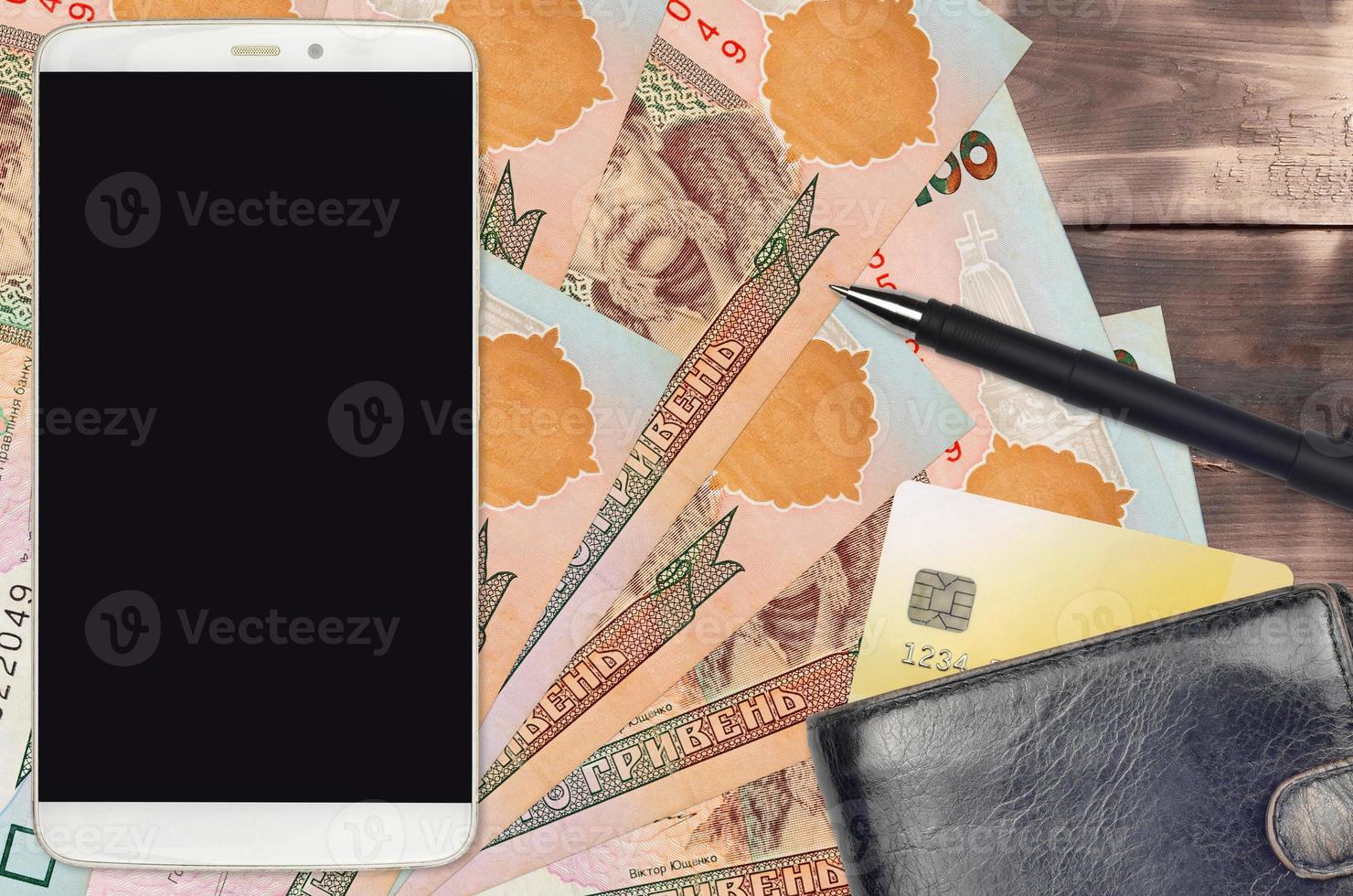 100 Ukrainian hryvnias bills and smartphone with purse and credit card. E-payments or e-commerce concept. Online shopping and business with portable devices photo