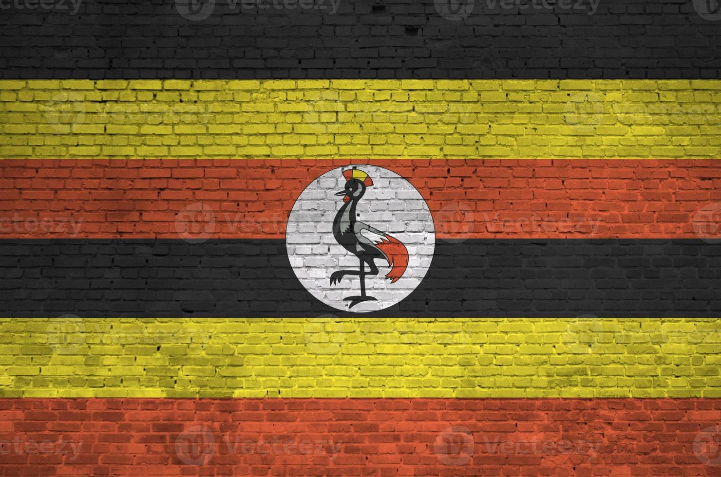 Uganda flag depicted in paint colors on old brick wall. Textured banner on big brick wall masonry background photo