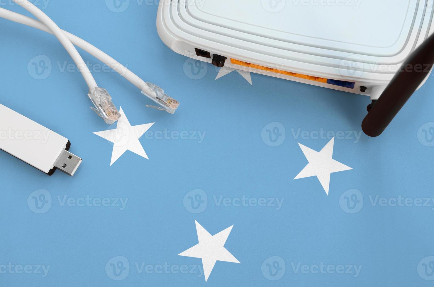 Micronesia flag depicted on table with internet rj45 cable, wireless usb wifi adapter and router. Internet connection concept photo