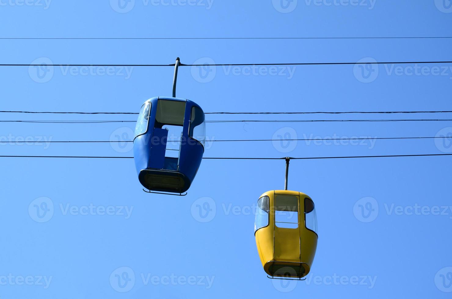 Blue and yellow passenger cable way cabins in the clear sky photo