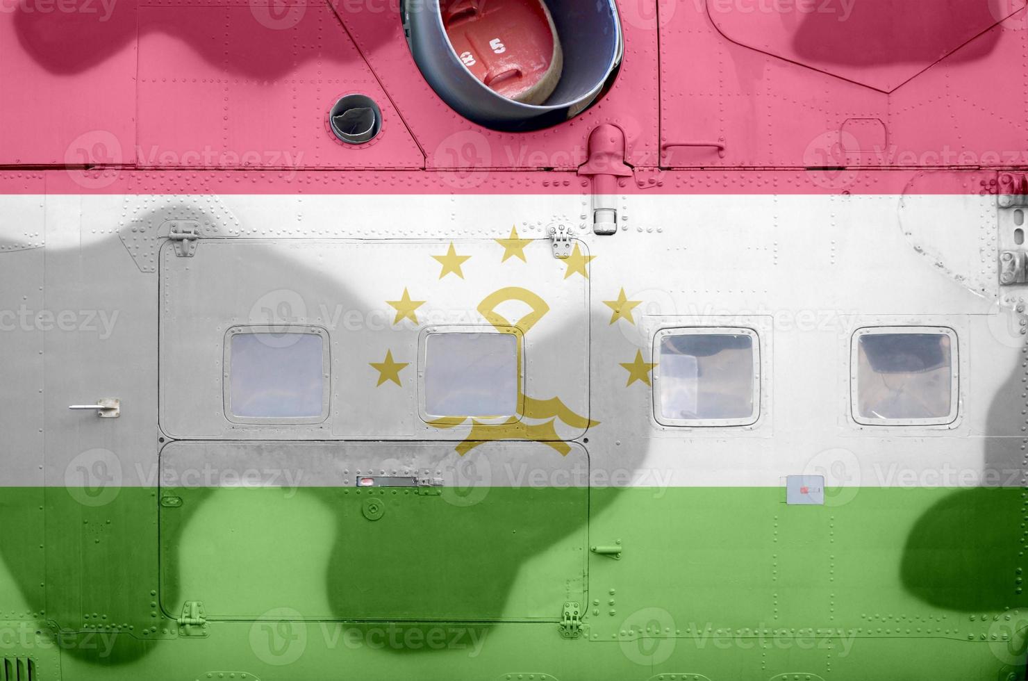 Tajikistan flag depicted on side part of military armored helicopter closeup. Army forces aircraft conceptual background photo