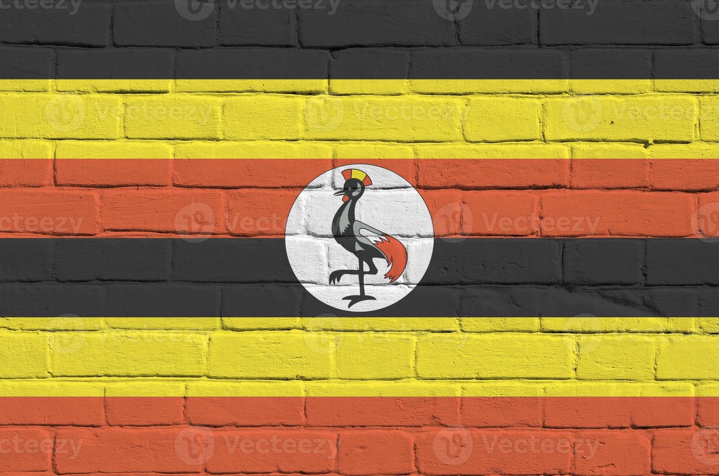 Uganda flag depicted in paint colors on old brick wall. Textured banner on big brick wall masonry background photo