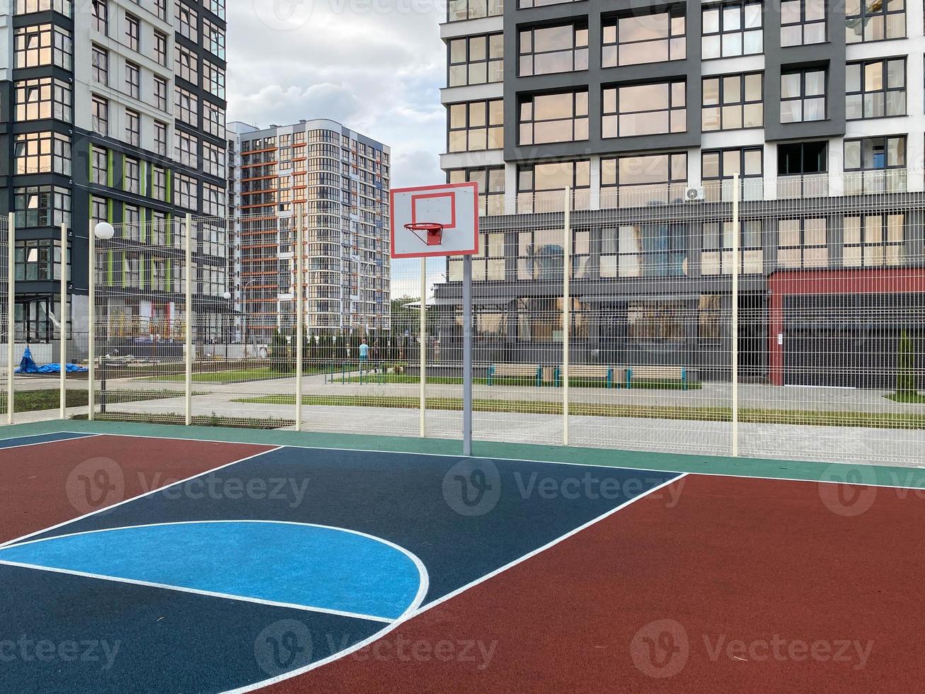 Empty sports basketball and football ground and deserted childrens playground in the yard of a residential building with empty photo