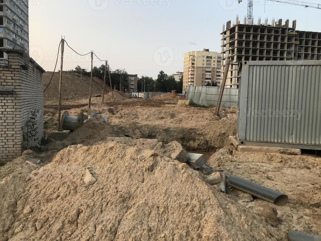 arena en un sitio de construcción. los constructores cavaron una zanja para tender comunicaciones. las tuberías de agua y alcantarillado están enterradas bajo un edificio alto foto