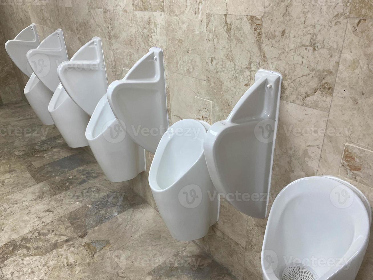 A Row Of Urinals In Tiled Wall In A Public Restroom photo