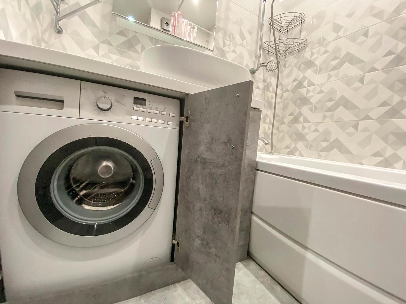 modern, stylish bath in a residential apartment. a huge sink made of white material, a stone countertop. there is a washing machine inside the closet. modern technology photo