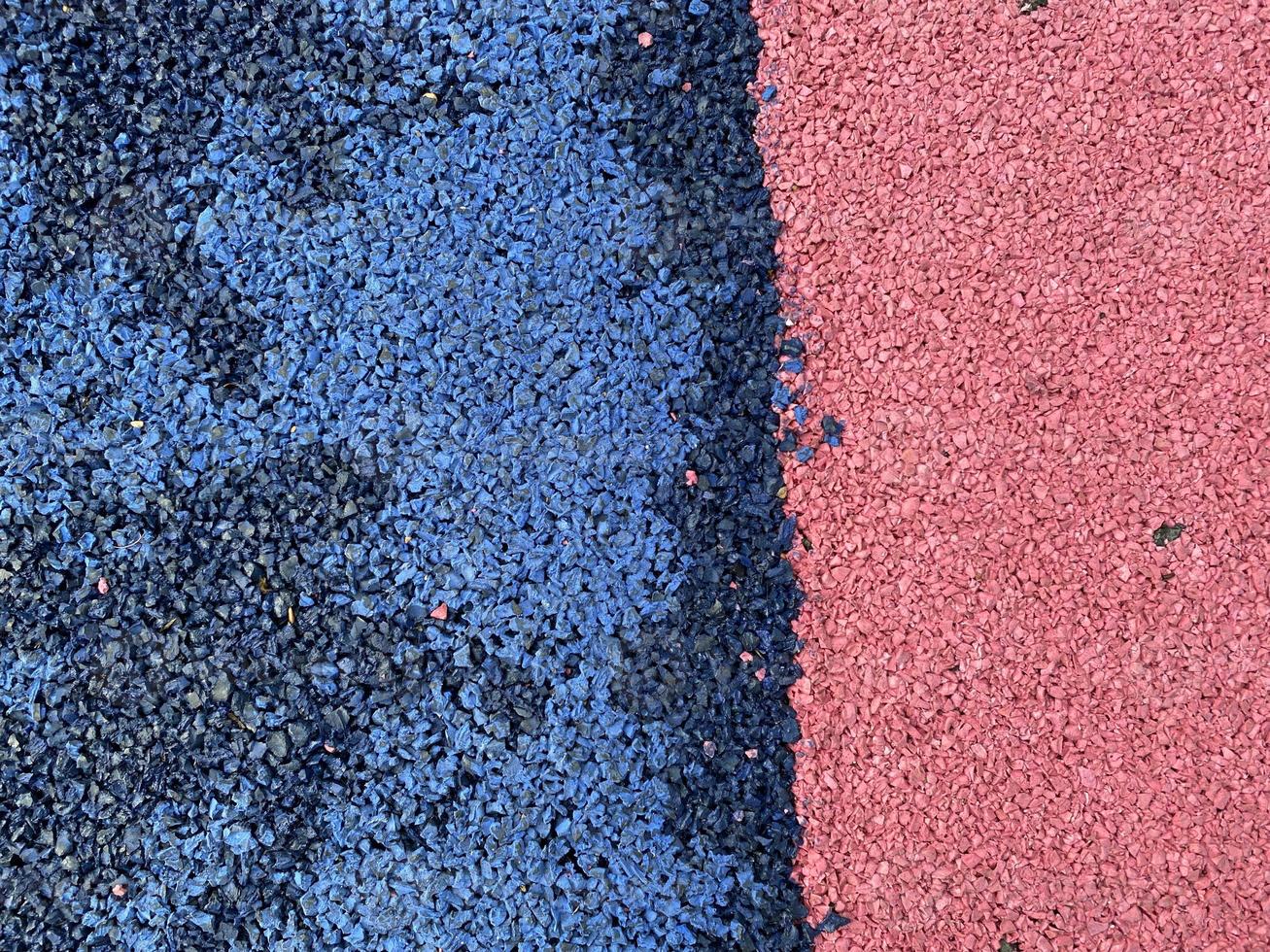 Blue and red texture of the soft rubber surface of the safe cover of the sports playground for workout made of pressed fine rubber photo
