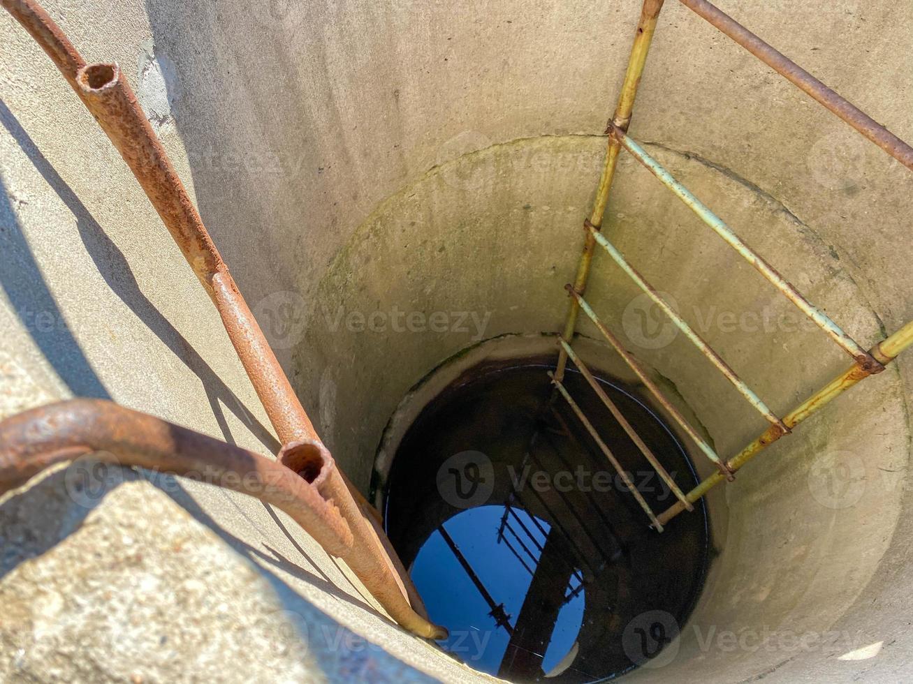 Profundo pozo oscuro vista de primer plano superior de anillos de hormigón hasta el fondo foto