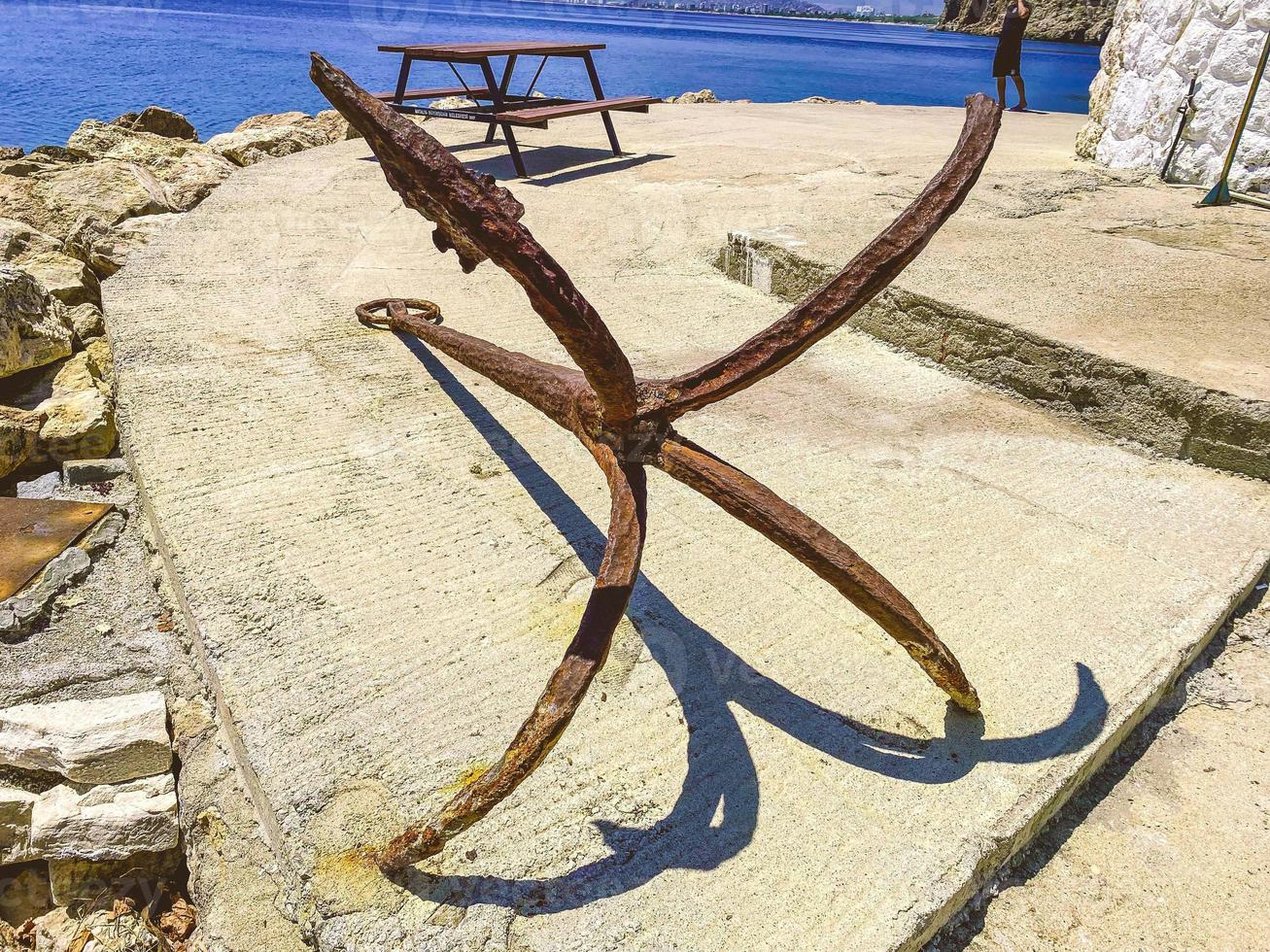 old, rusty anchor on the seashore. at the port with ships and yachts there is an anchor. tourists can see rust at anchor. marine stopper in rust, water rust photo
