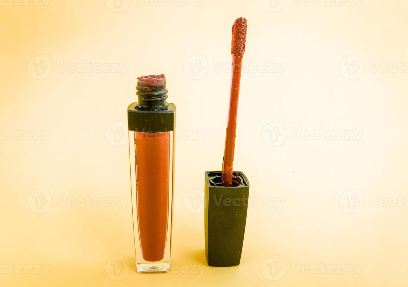 Liquid lipstick open tube and lipstick smear smudge isolated on white background. Makeup composition. Red coral lip gloss swatch photo