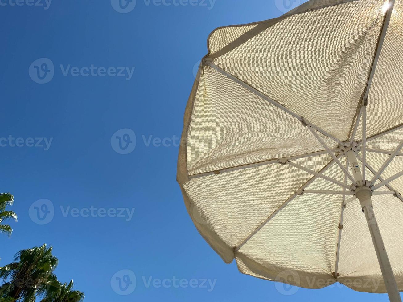 Looking up at a parasol against a blue sky, on a warm day photo