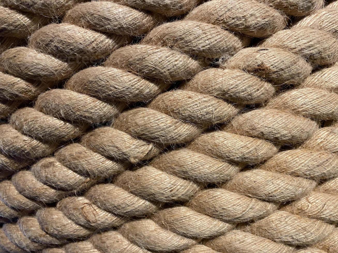 Diagonal strands of a new thick sisal and hemp rope with twisted braided fibers in a full frame close up background texture photo