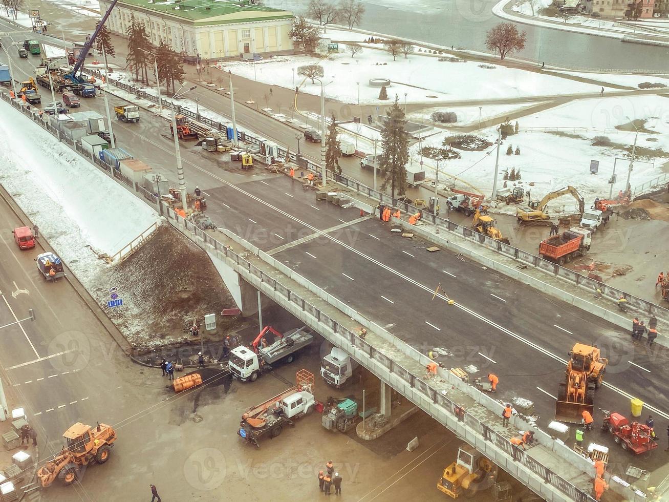 construction of a new bridge in the city center, view from above. construction machinery is working on laying new asphalt. marking in winter photo