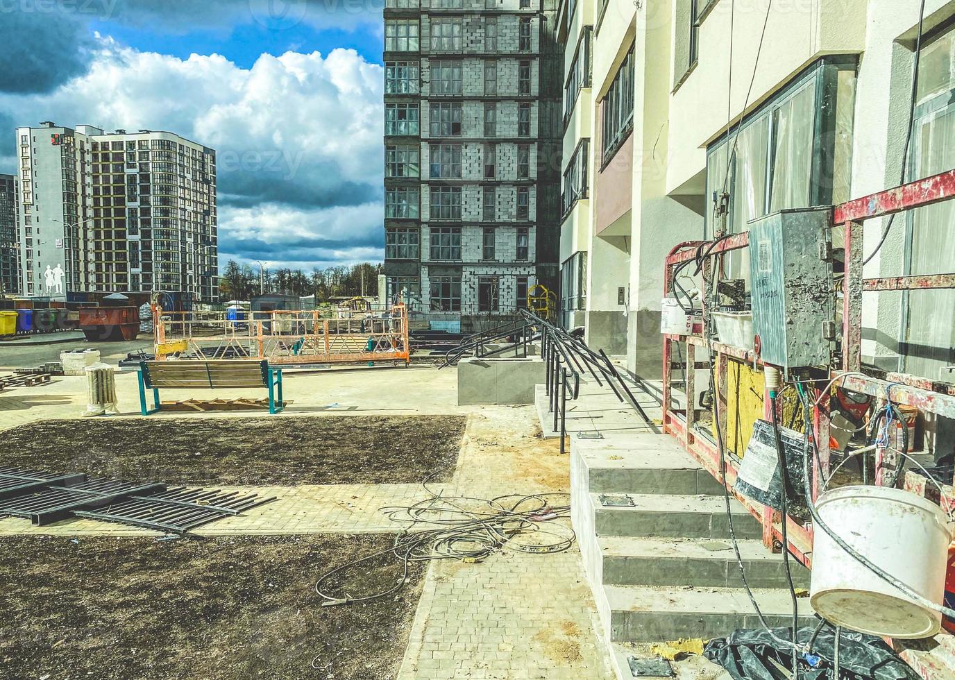 construction of a new microdistrict in the city center. concrete block house. white paint is applied to the facade of a high-rise building. painter on a crane paints a house photo