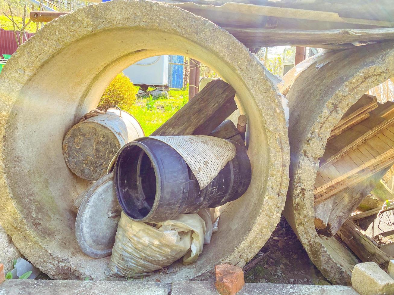 anillos de hormigón para el pozo. enormes y voluminosos anillos se utilizan como depósito de basura. dentro de los anillos: un barril de goma negro, un tronco de madera foto