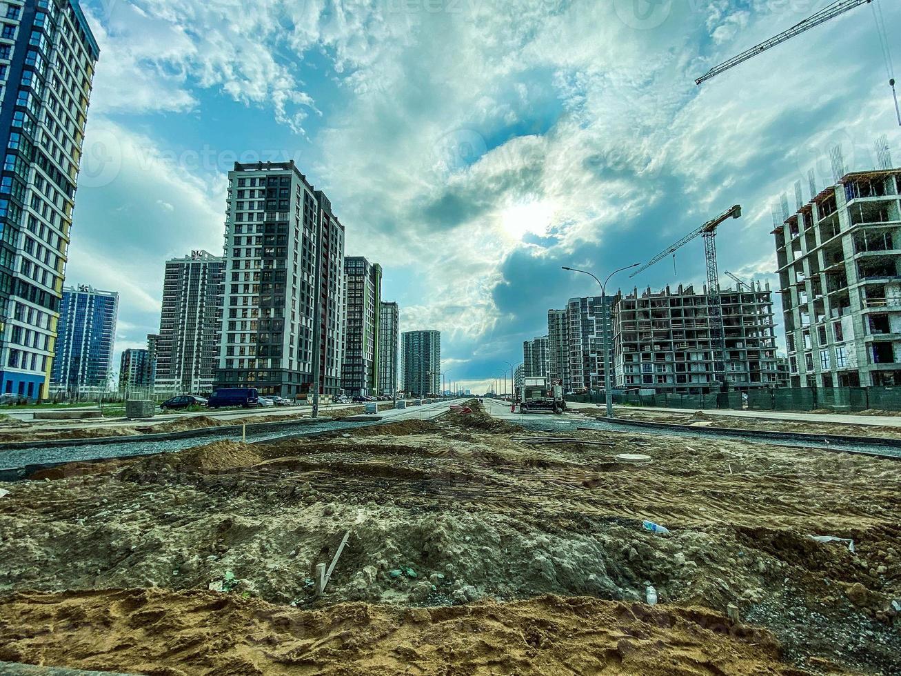 construction of a new residential complex in the city center. high houses made of concrete and glass for people's lives. they lay a road nearby and prepare the soil for laying the material photo