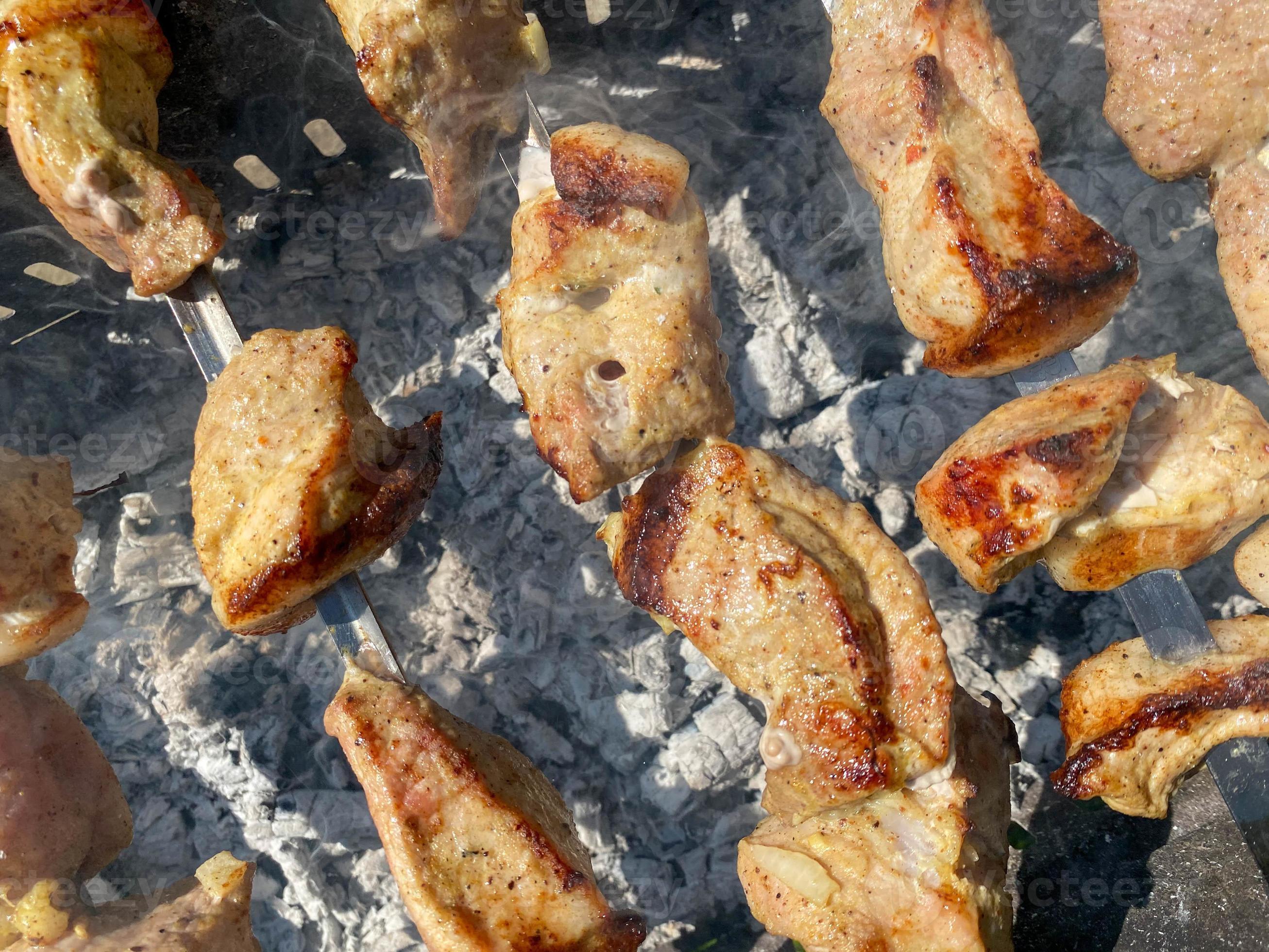 Tasty juicy pork barbecue cooking on metal skewers on charcoal outdoors grill with fragrant fire