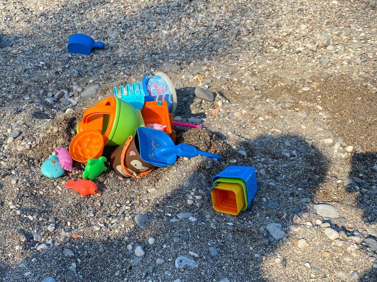 Childrens toys for playing in the sandbox buckets and molds with shovels on a pebble beach near the sea photo