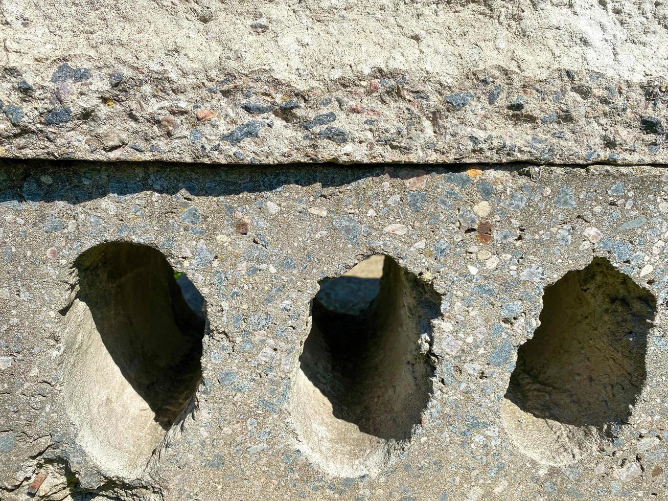 Surface texture of solid gray construction concrete cement slab with holes. The background photo