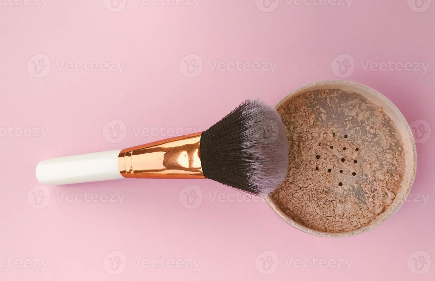 powder brush on a bright pink background. face powder and brush. loose matte powder to match the skin. mineral powder for make-up and tone creation photo