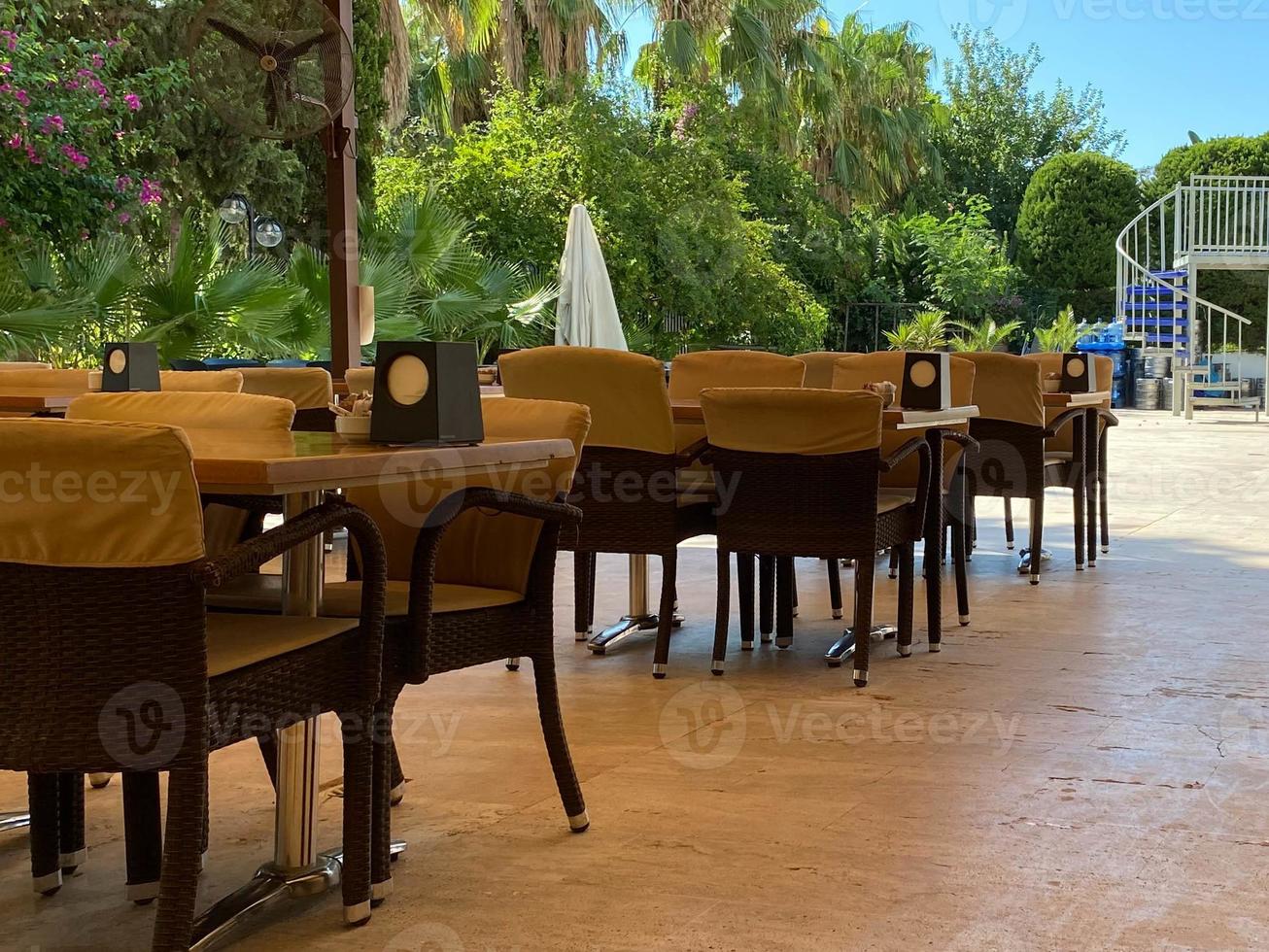 Beautiful view of outdoor tables. Blue chairs and orange umbrellas on green palm trees and blue sky background. Key West, Florida. USA photo