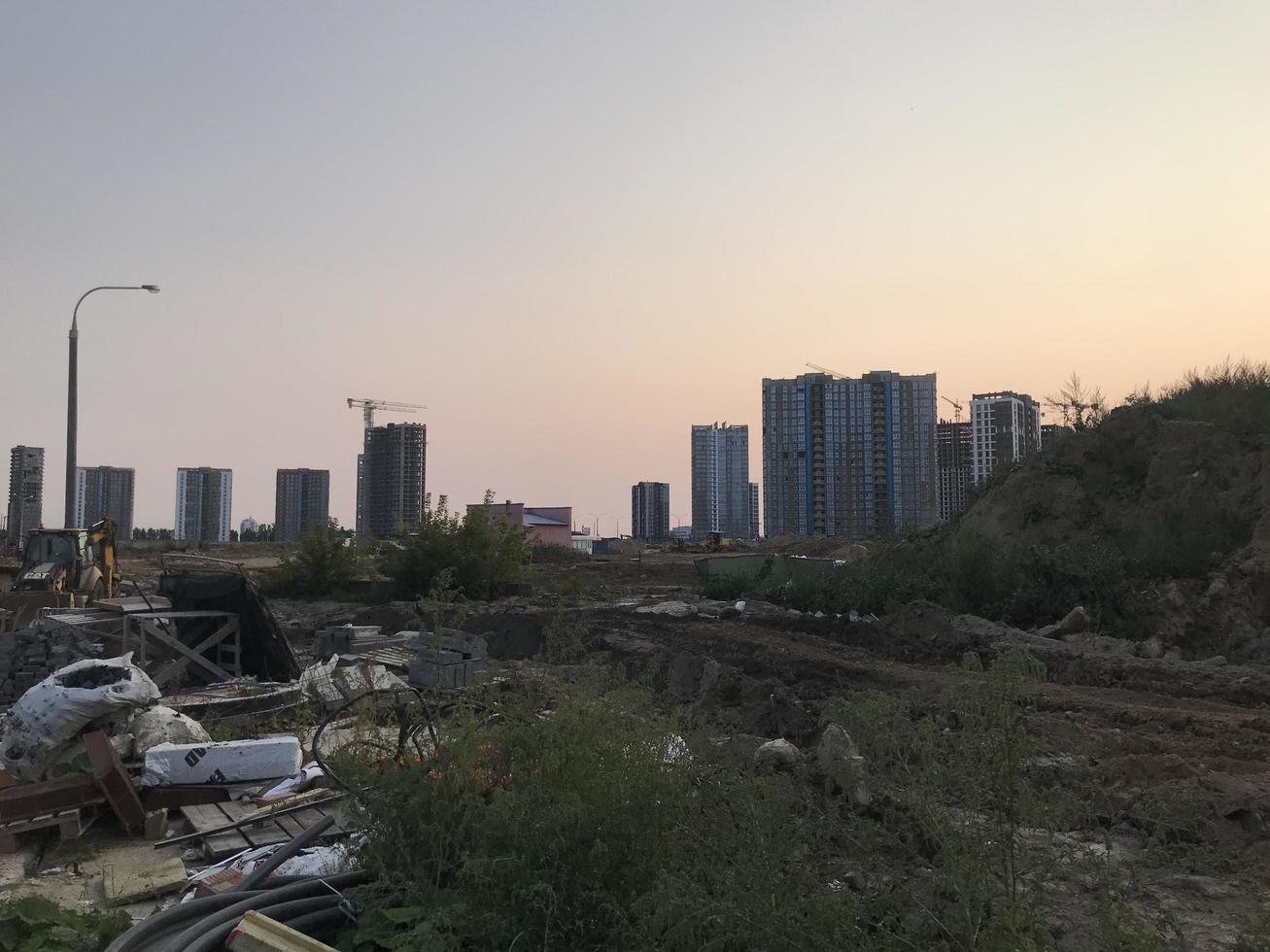 construction waste lies at the construction site. next to the construction of a new microdistrict. new houses are built of concrete and glass photo
