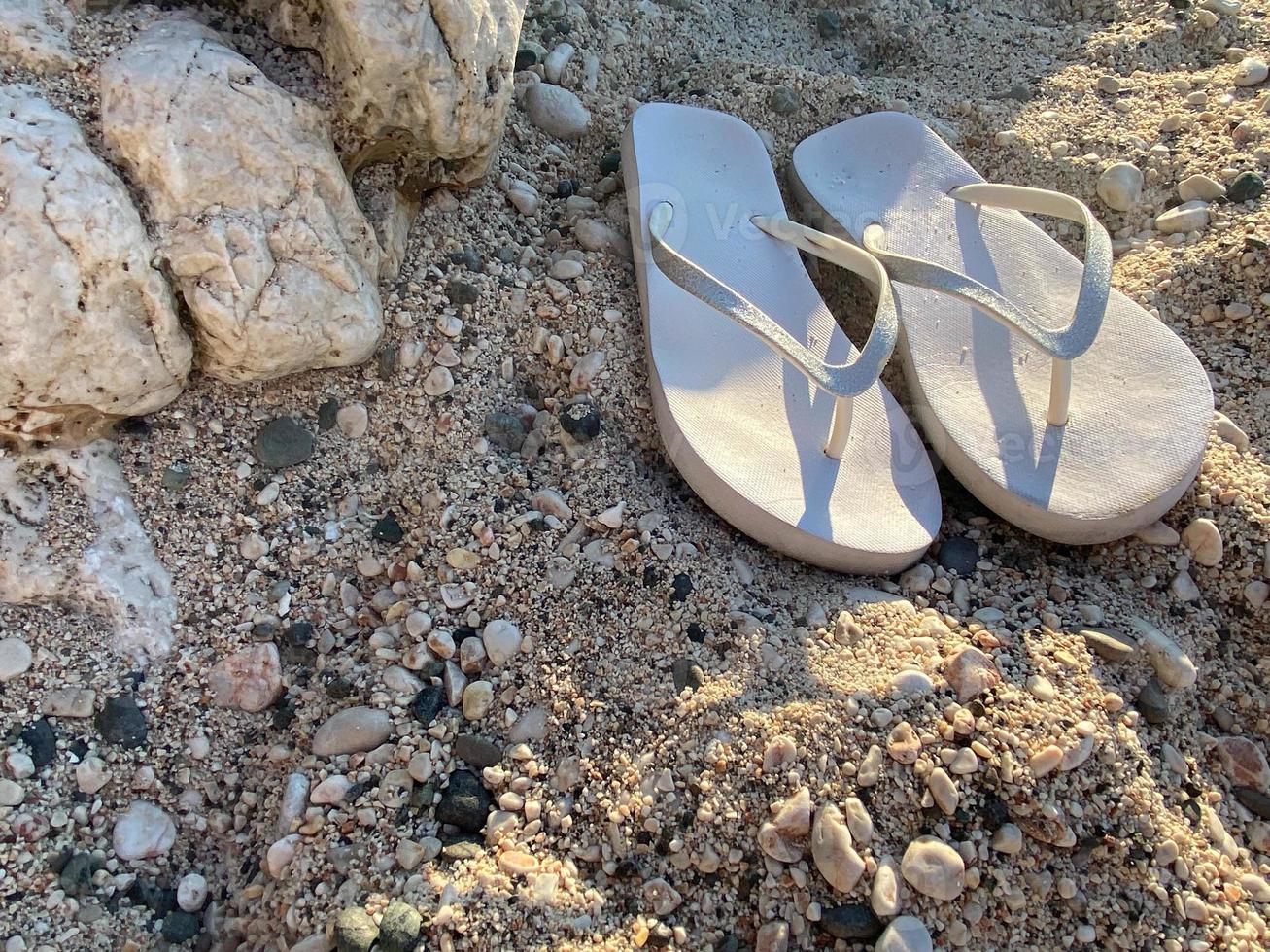flip-flops on a light sand. Texture of light sand. The concept of a beach holiday. Summer concept. Flat lay, top view, copy space photo