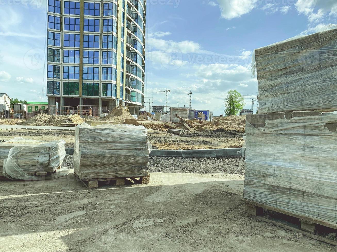 construction of a new residential area in the city. construction of high, multi-storey buildings from building materials. on the site there are blocks under the film photo