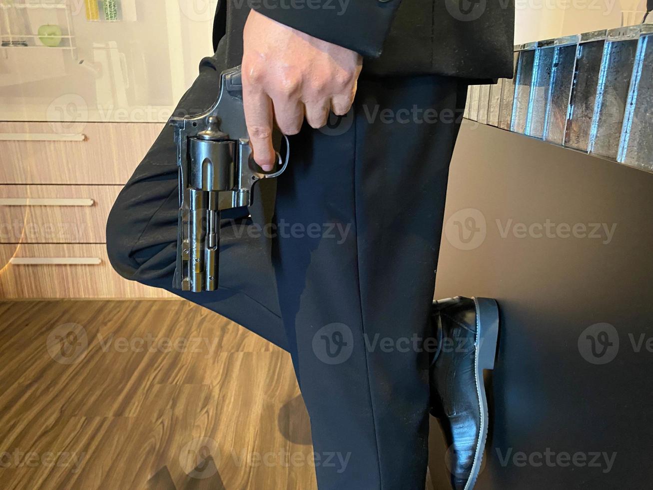 Close up on hand of unknown caucasian man holding a gun in by his leg while standing outdoor in sunny day - handgun criminal or self-defense concept with copy space photo