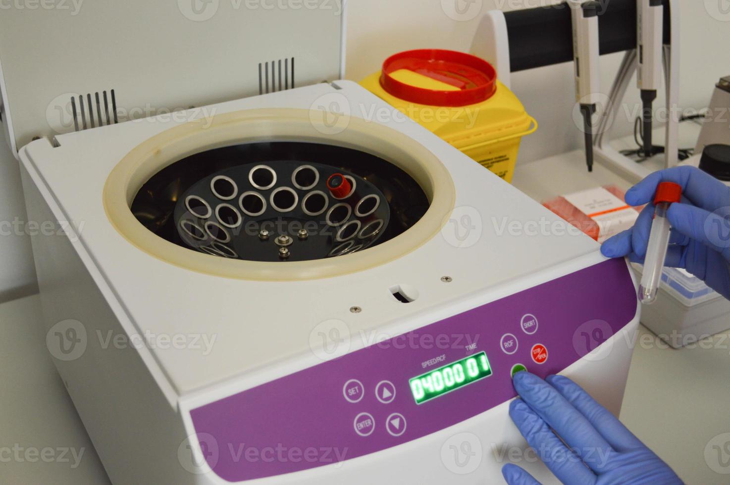 Scientist putting test tube into centrifuge photo