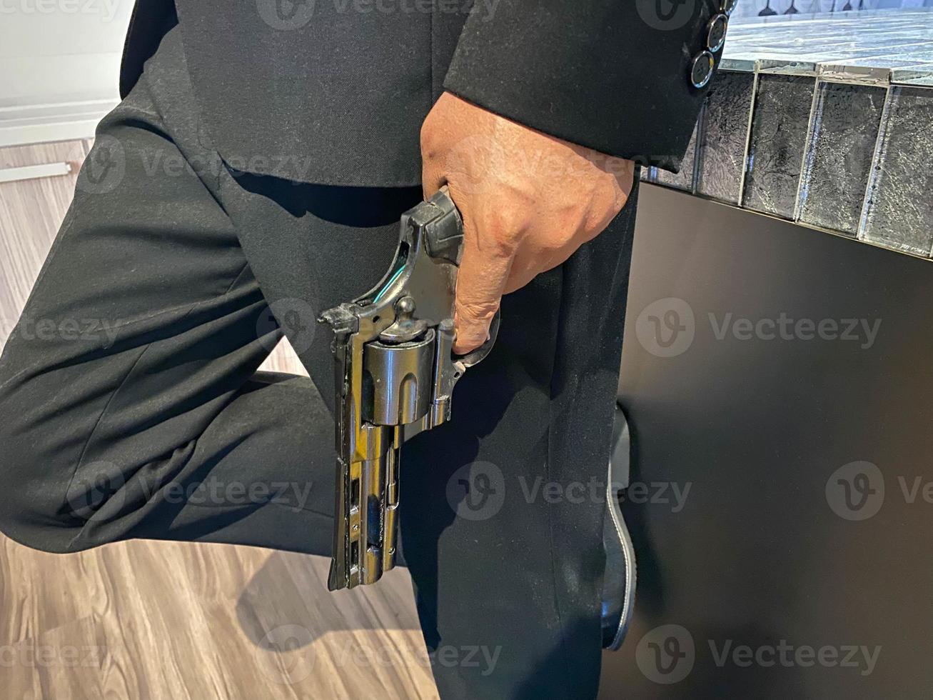 Close up on hand of unknown caucasian man holding a gun in by his leg while standing outdoor in sunny day - handgun criminal or self-defense concept with copy space photo