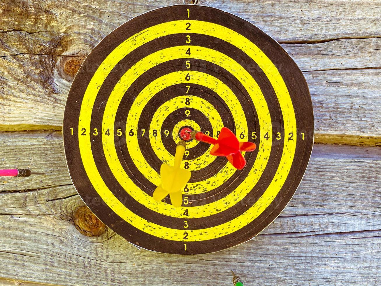 active outdoor games. darts with darts on a rustic log background. shooting a dart with a feather straight at the target. yellow field with marks points. game of accuracy photo