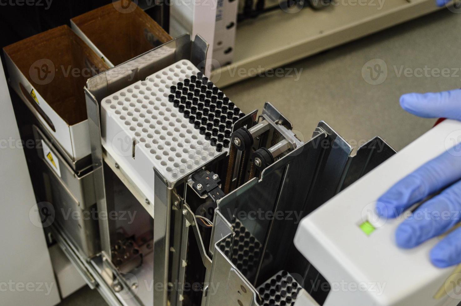 a doctor in gloves performs a cassette with a reagent for performing studies in the analyzer. blood tests in the laboratory. analyzer to run tests. laboratory diagnostic equipment photo