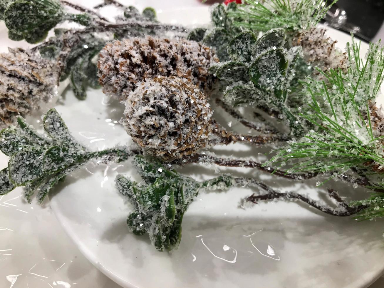 Christmas mock up, grey ceramic or clay plate top view for text or design, spruce or pine branch covered in snow and cones on a wooden rustic table photo