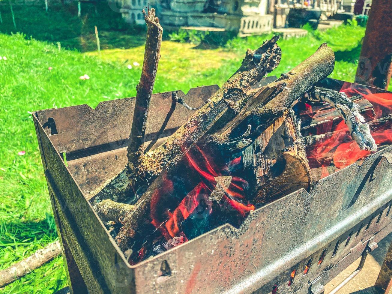 brazier with smoldering wooden firewood. a small, metal, rusty brazier for cooking shish kebabs. tongues of flame in an enclosed space. cooking food photo