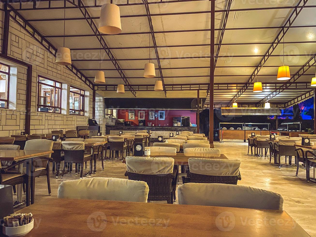 resto de turistas en un hotel caro. la comida se sirve en comedores comunes al aire libre. muebles de cafetería, acogedoras sillas de tela y mesas de mimbre con cubiertos foto