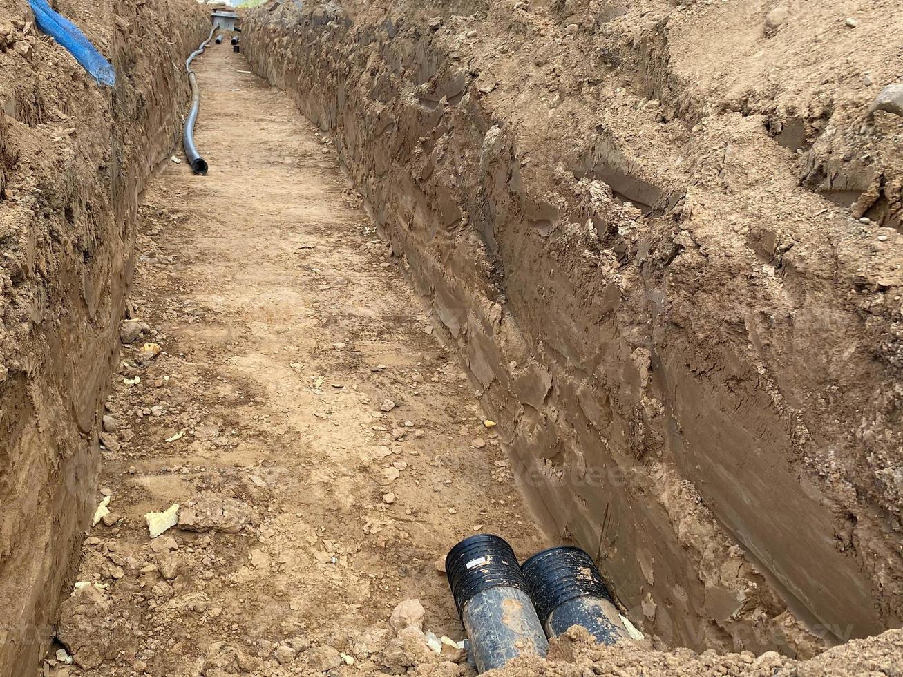 Large industrial modern new large diameter polyethylene plastic water pipes lie in a pit underground at a construction site during a water pipe repair photo