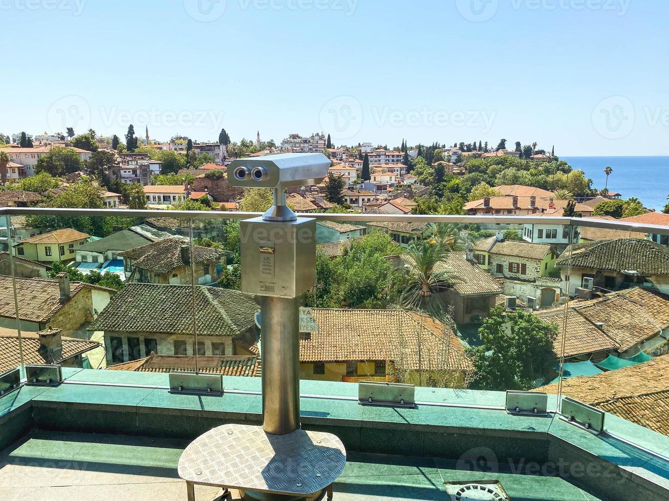 at the height of the houses of local residents with a tile roof. binoculars for tourists are installed on the roof. binoculars for viewing on a metal pedestal photo