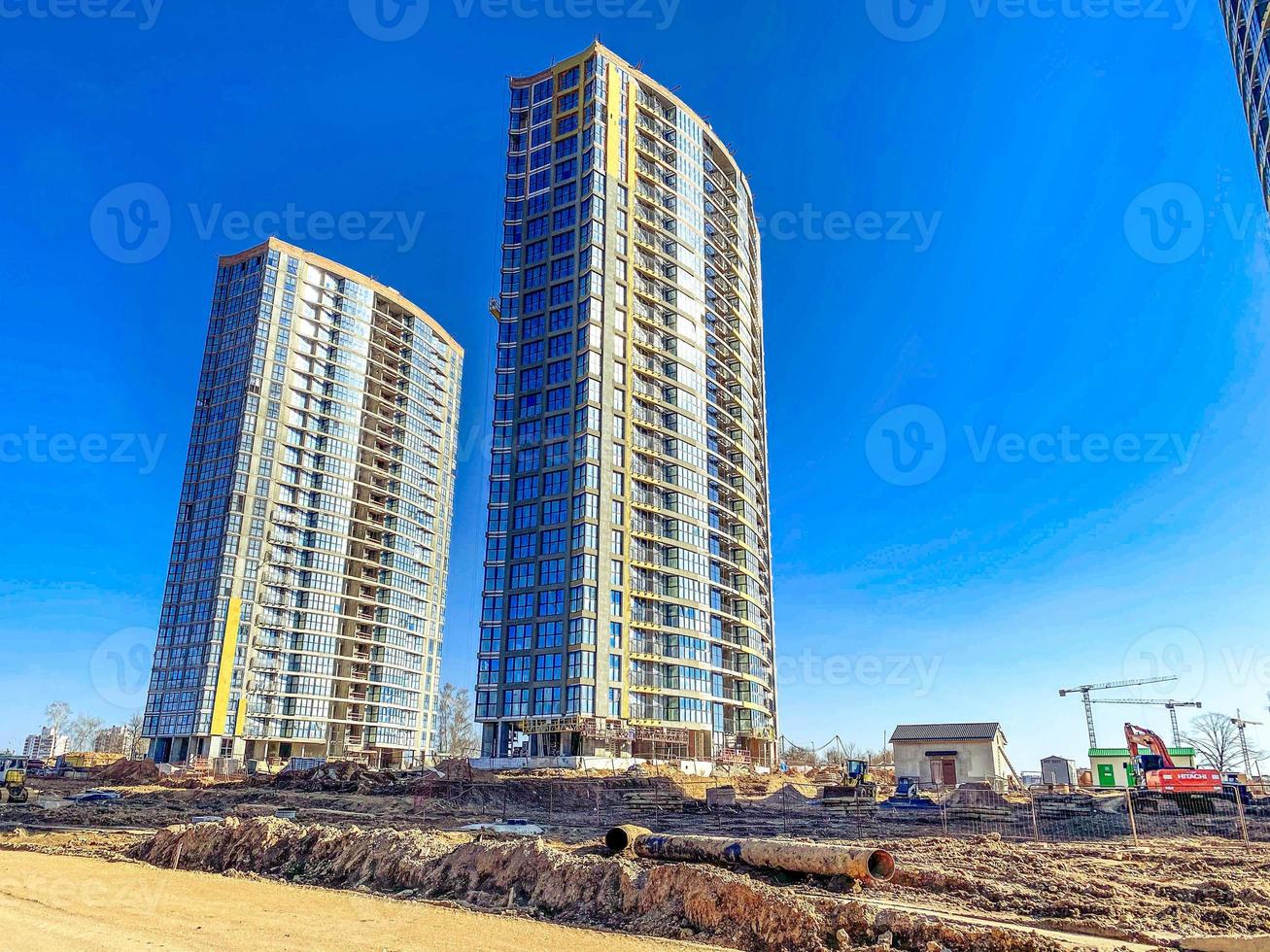 construcción de un nuevo microdistrito en el centro de la ciudad. edificios altos y altos hechos de hormigón y vidrio junto a un terraplén de arena. foso para tendido de comunicaciones foto