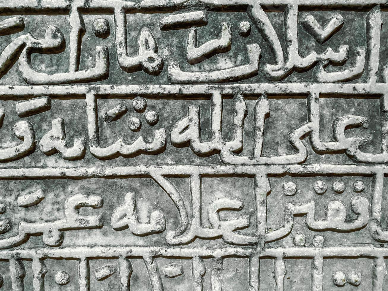 stone texture. letters are carved on a heavy, sandy board. ancient font, large, tall words are carved with a thick and twisted line, the ancient creativity of the tribes on a gray board photo